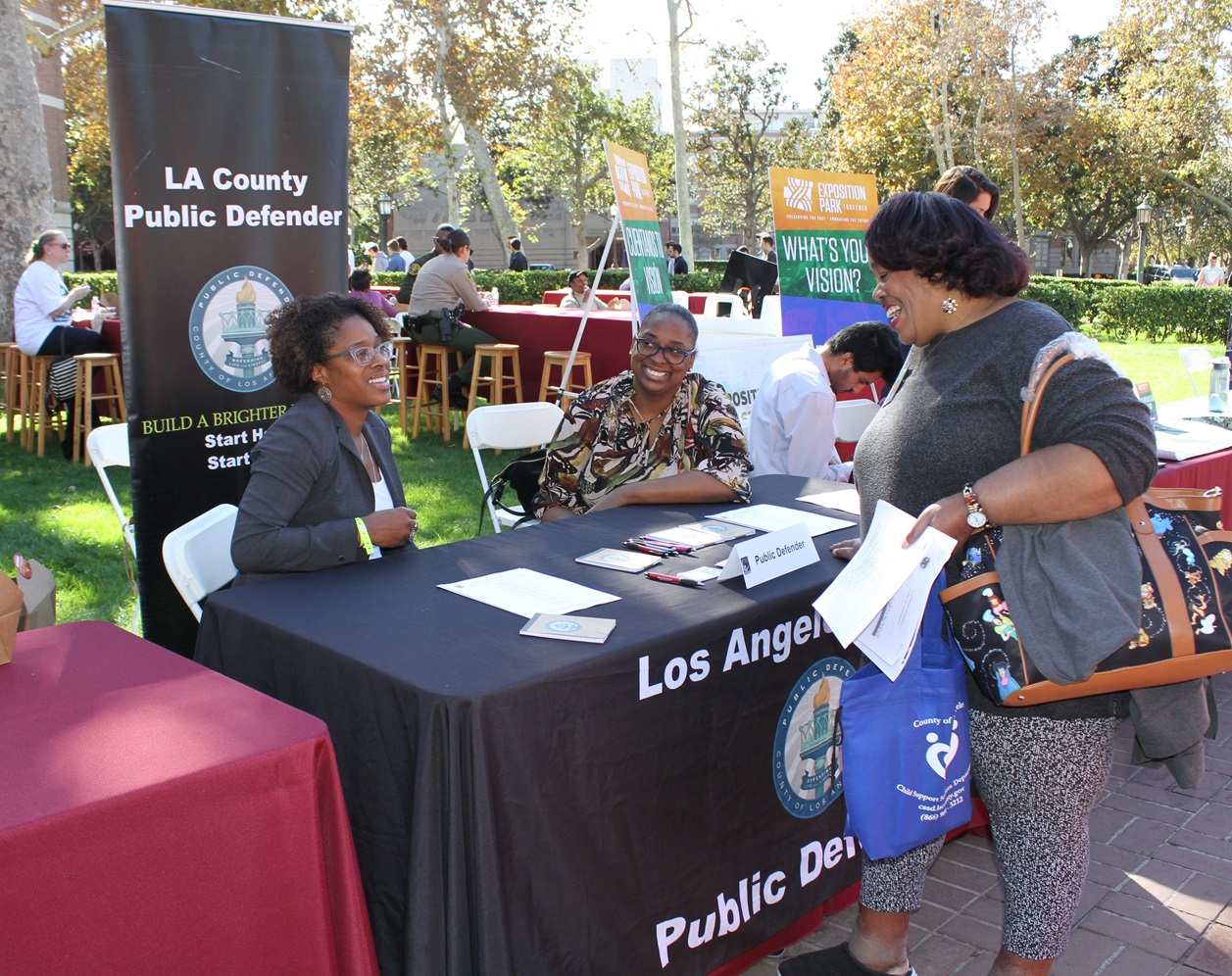 Public defenders talking with a passerby about their booth.