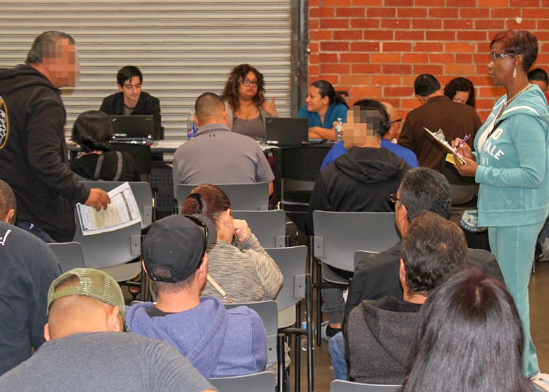 People sitting down in a public meeting with the camera facing their backs.