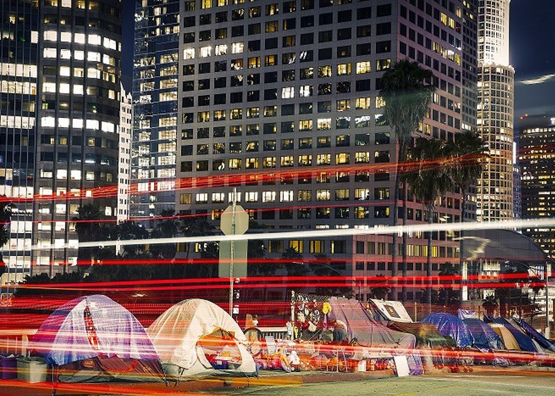 Homeless people living in tents near downtown LA at night.