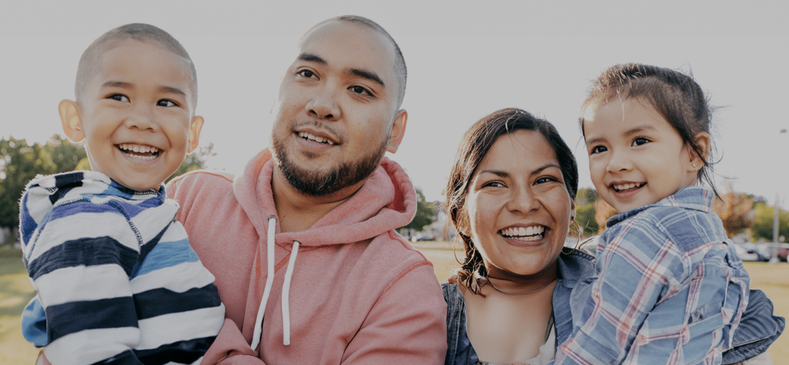 A family of immigrants smiling in front of the camera.